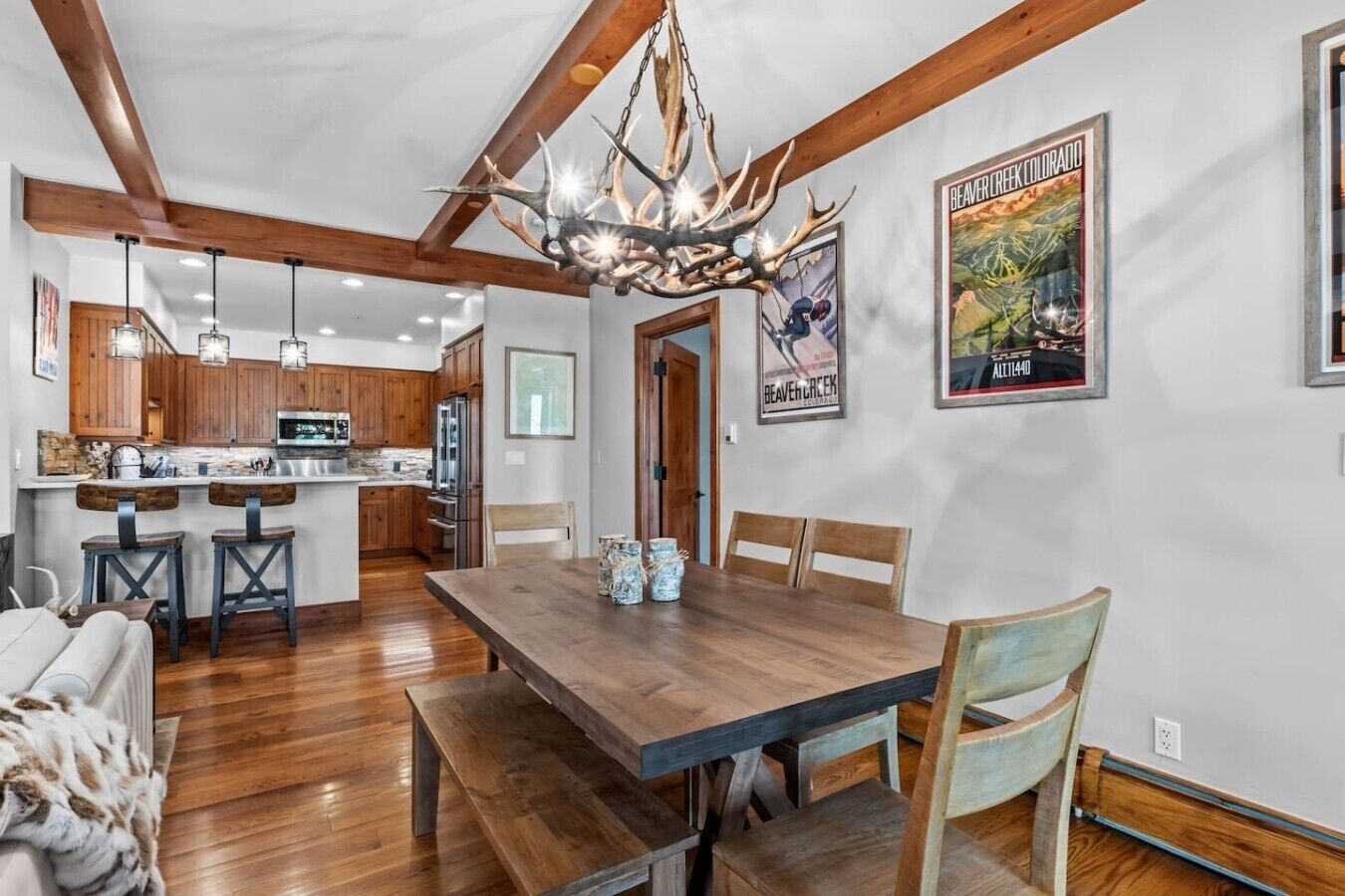 A dining area with a wooden table, benches, and a chandelier.