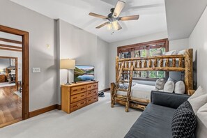 Ein Schlafzimmer mit Etagenbett, einem Holzkleiderschrank, einem Fernseher und einem Deckenventilator.