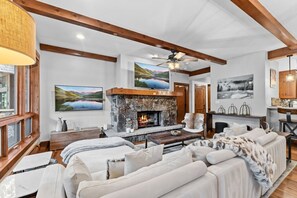A spacious living room with a stone fireplace, wooden beams, and large windows. - Ski In/Out Beaver Creek I Slopeside Retreat W/Pool (Avon)