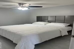 A bedroom with a bed, a ceiling fan, and a headboard. - Cozy 2-bedroom in perfect Port Richey with AC (Port Richey)