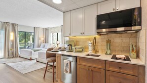 A modern kitchen with a dishwasher, a microwave, and a large stove. There is a dining area with a table and chairs. - Lake View Studio near Universal & Epic (Orlando)