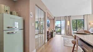 A modern kitchen with a refrigerator, a dining area with a table and chairs, and a view through a glass door. - Lake View Studio near Universal & Epic (Orlando)