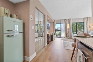 A modern kitchen with a refrigerator, a dining area with a table and chairs, and a view through a glass door. - Lake View Studio near Universal & Epic (Orlando)