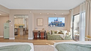 A hotel room with two beds, a dining area, a kitchenette, and a large window with a view of a castle. - Lake View Studio near Universal & Epic (Orlando)