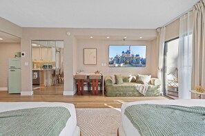 A hotel room with two beds, a dining area, a kitchenette, and a large window with a view of a castle. - Lake View Studio near Universal & Epic (Orlando)