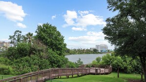 A park with a wooden boardwalk, grassy areas, and a lake. - Lake View Studio near Universal & Epic (Orlando)