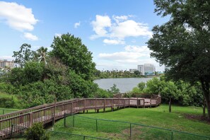 A park with a wooden boardwalk, grassy areas, and a lake. - Lake View Studio near Universal & Epic (Orlando)