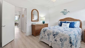A bedroom with a bed, a dresser, a mirror, a ceiling fan, and a wall decoration. - Beach Proximity Condo w/ Pool & Dining Access (Naples)