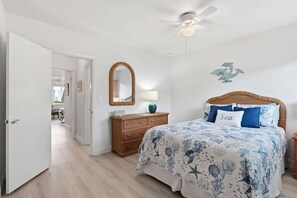 Ein Schlafzimmer mit einem Bett, einem Schminktisch, einem Spiegel, einem Deckenventilator und einer Wanddekoration.