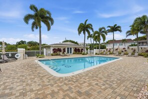 Ein Swimmingpool mit Liegestühlen, Palmen und einem Haus im Hintergrund.