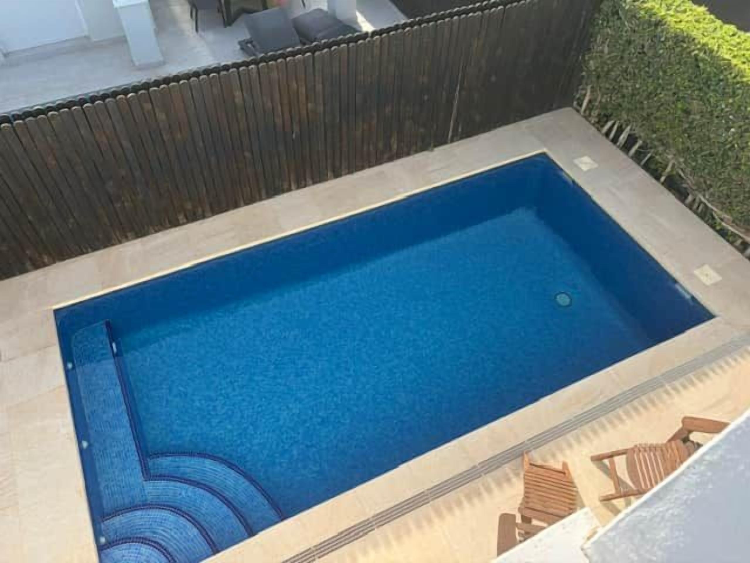 Una piscina rectangular con borde de azulejos y un desagüe circular pequeño en el centro.