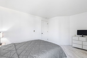 Ein Schlafzimmer mit einem Bett, einem Fernseher und einer Kommode.