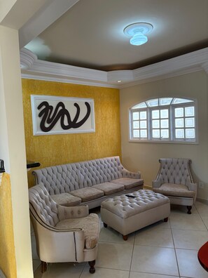 Ein Wohnzimmer mit einem Ecksofa, einer Liege und einem gepolsterten Ottomanen.