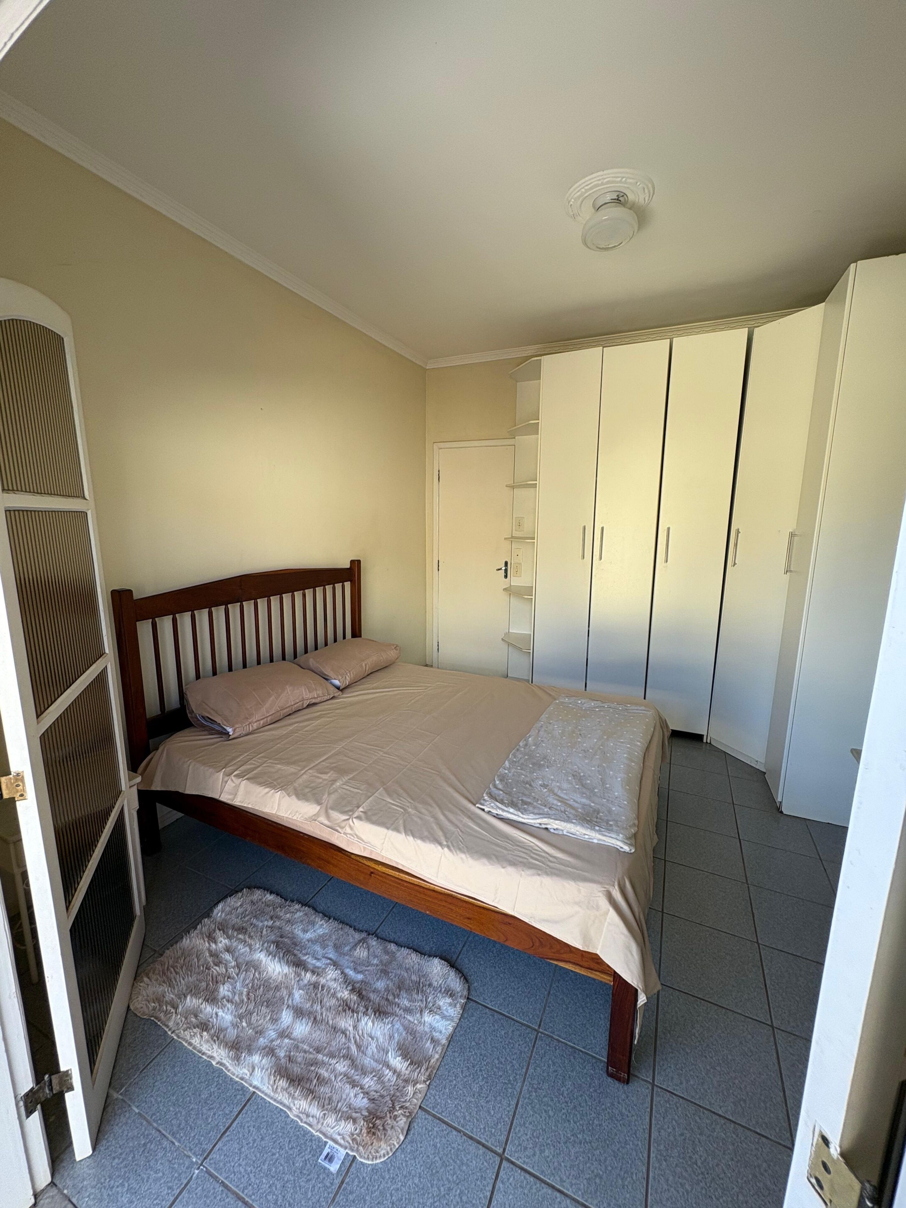 Una camera da letto con un letto, un armadio, una porta e un tappeto piccolo.