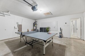 Ein Tischtennistisch in einem Raum mit weißen Wänden, einer Deckenlampe und einer Tür.