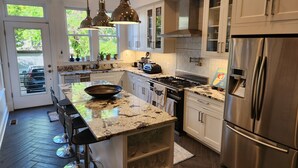 Una cucina moderna con isola centrale, elettrodomestici in acciaio inossidabile e illuminazione a sospensione.
