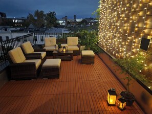 A rooftop terrace with wicker furniture, a wooden floor, and string lights. - Charming 2,700ft 3-bedroom townhome in heart of DC (Washington)