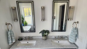 Un bagno con due lavandini, una pianta in vaso e uno specchio.