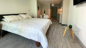 Une chambre à coucher avec un lit, une table de chevet et un téléviseur fixé au mur.