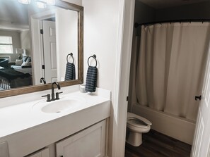 Ein Badezimmer mit einem weißen Waschbecken, einem Spiegel, einem Handtuchhalter und einer Toilette.
