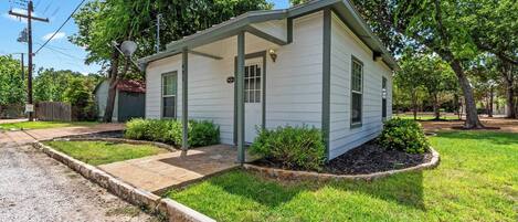 A single-story house with a front porch, a small garden, and a gravel driveway.