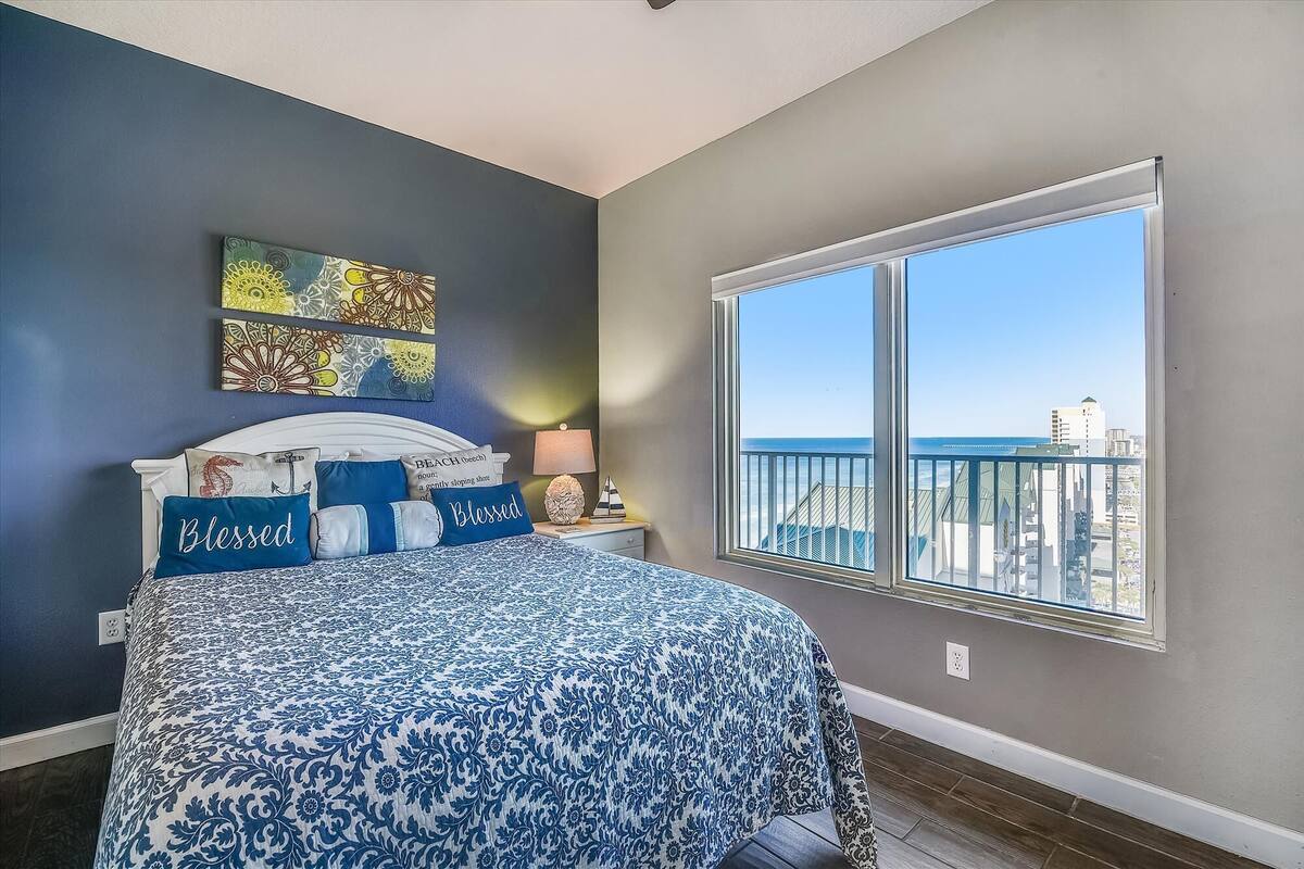 Ein Schlafzimmer mit einem Bett, einem Fenster mit Blick auf die Stadt und Kunstwerken an der Wand.