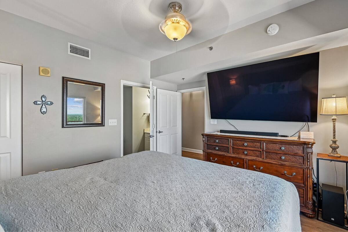 Ein Schlafzimmer mit Bett, Fernseher, Kommode und Deckenventilator.