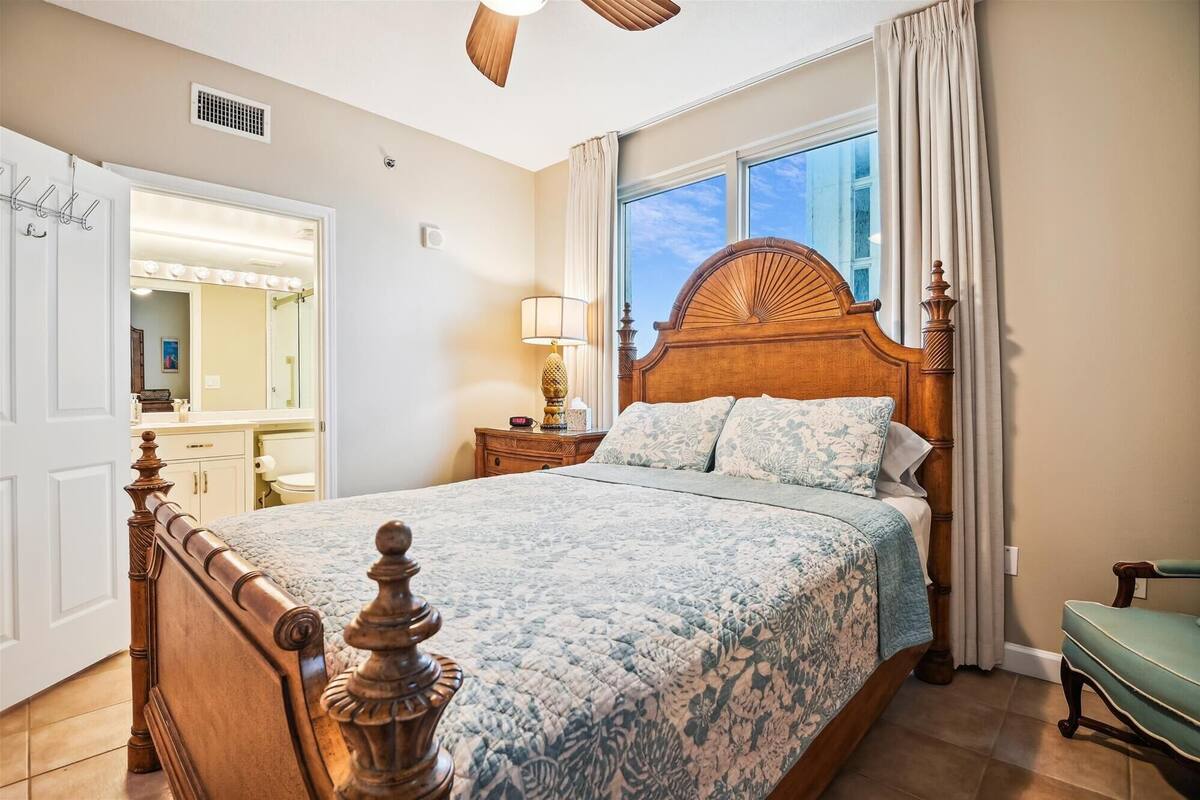 Ein Schlafzimmer mit einem großen Bett, einem Schminktisch mit Spiegel und einem Fenster mit Vorhängen.