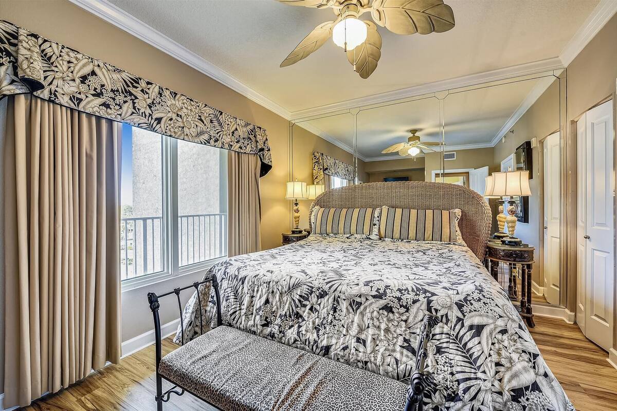 Ein geräumiges Schlafzimmer mit einem großen Bett, einer Liege und einem Deckenventilator.