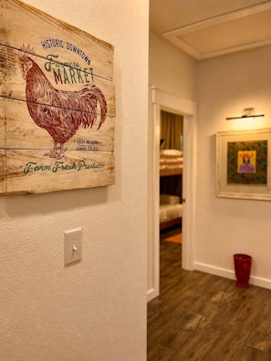 A hallway with a rustic wooden sign, a light switch, and a red bucket.
