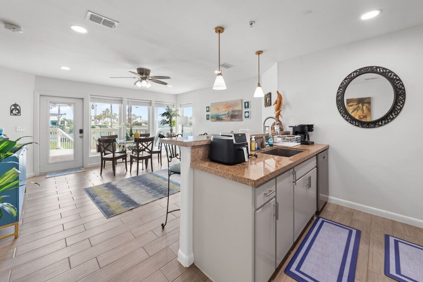 A modern kitchen with a central island, pendant lights, and a view to a balcony.