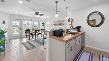 A modern kitchen with a central island, pendant lights, and a view to a balcony.