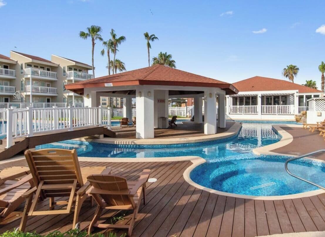 Un área de piscina con sillas de descanso, un pabellón y una piscina con cubierta de madera.