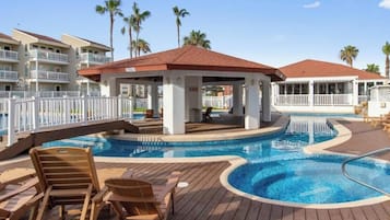 Un área de piscina con sillas de descanso, un pabellón y una piscina con cubierta de madera.