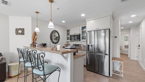 Una cocina moderna con una isla central, electrodomésticos de acero inoxidable e iluminación colgante.
