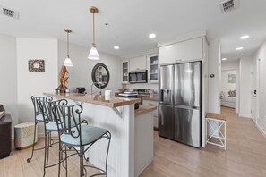 A modern kitchen with a central island, stainless steel appliances, and pendant lighting. - Huge Patio Steps to Pool & Tennis • Beach Retreat (South Padre Island)