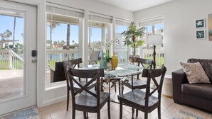 Una habitación amplia con balcón, una mesa de comedor con sillas, un sofá y una lámpara.