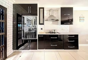 A modern kitchen with black cabinets, a stainless steel range, and a large window. - Have the Entire House to Yourself (Johannesburg)