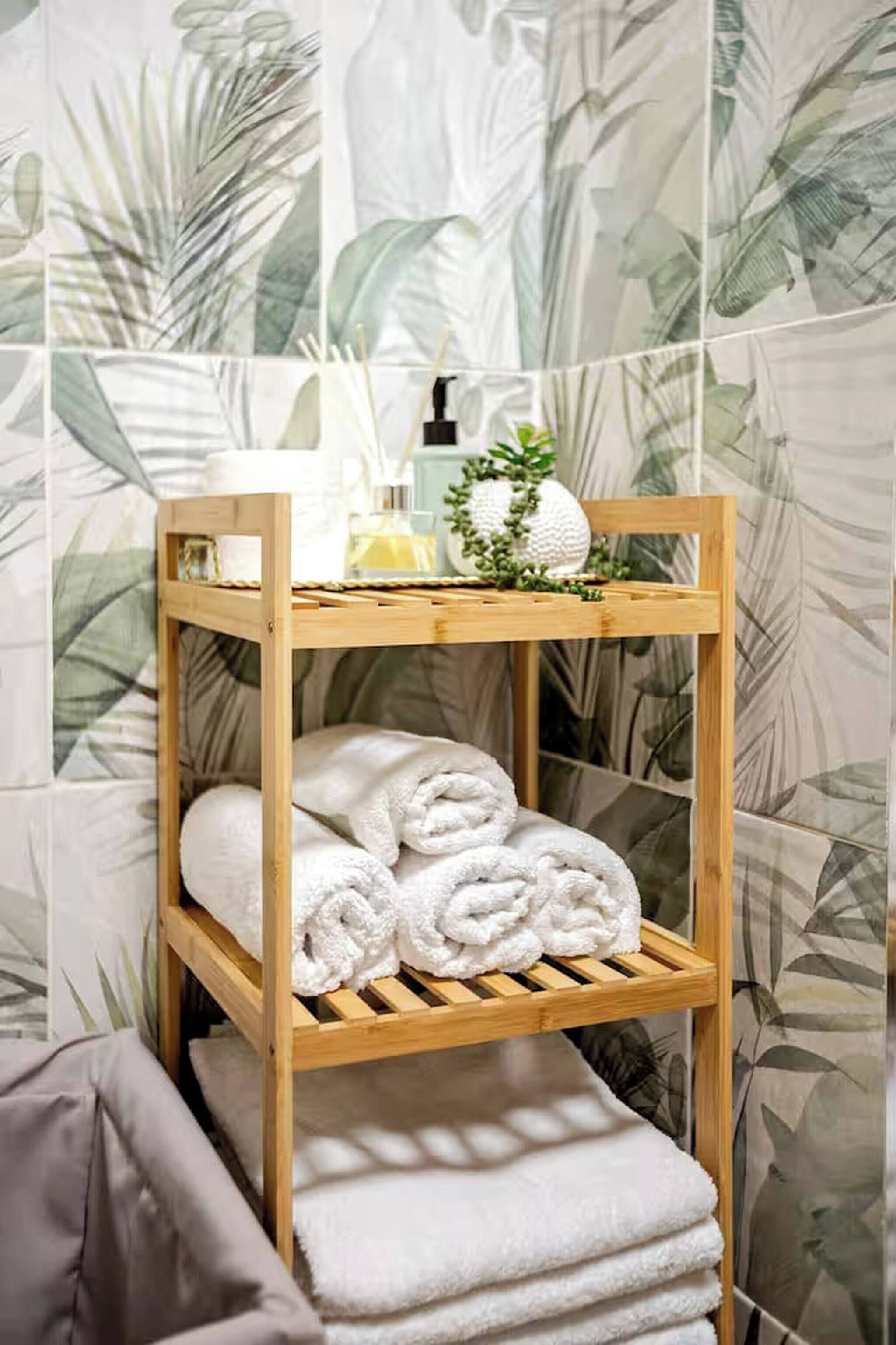 Een houten plank met opgerolde handdoeken en een kleine plant.