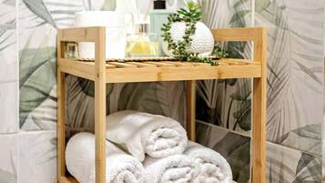 Een houten plank met opgerolde handdoeken en een kleine plant.