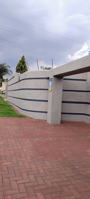 A concrete wall with horizontal lines, a sign, and a paved area.