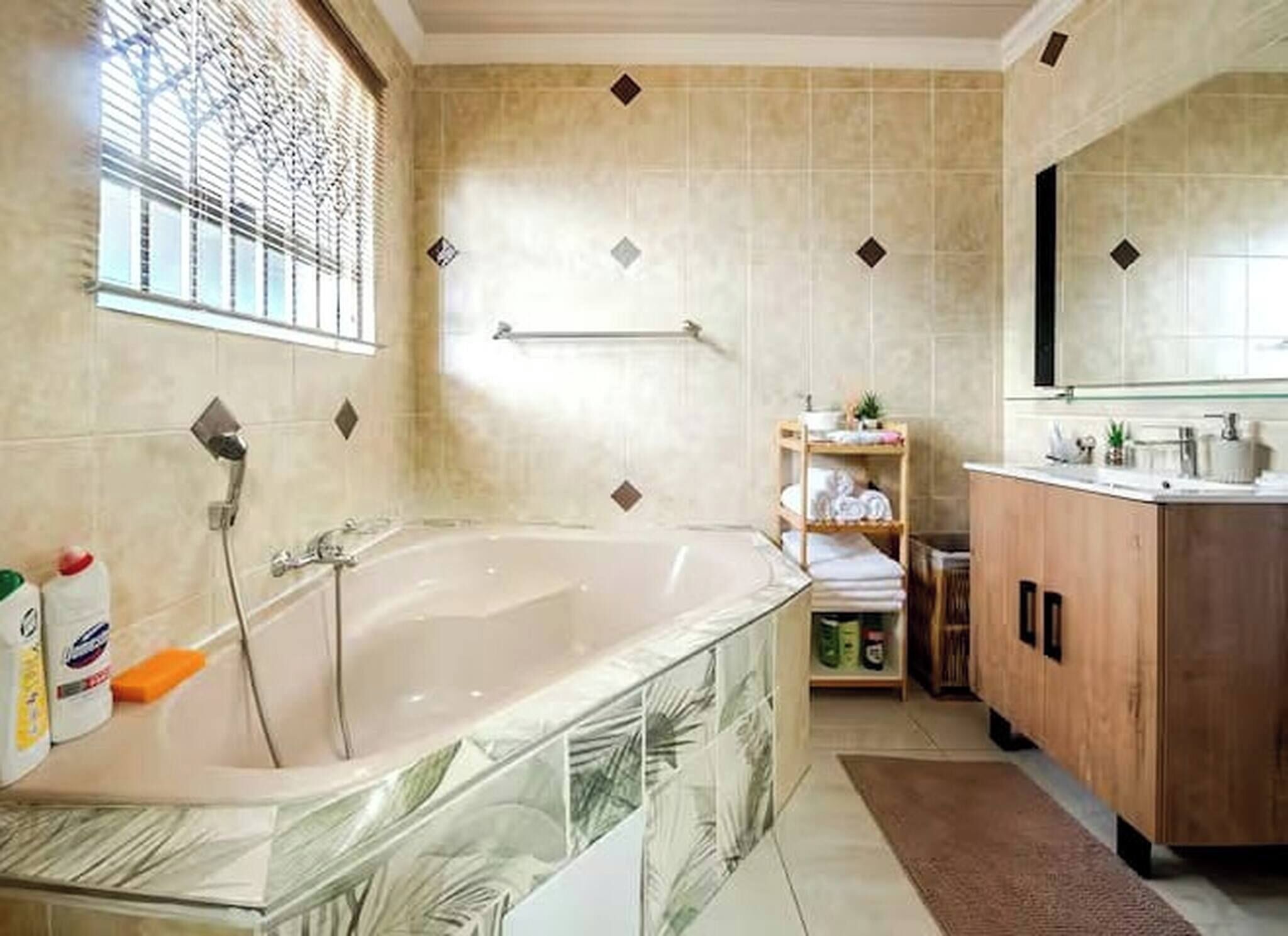 A bathroom with a bathtub, a shower, a shelf with towels, and a mirror.