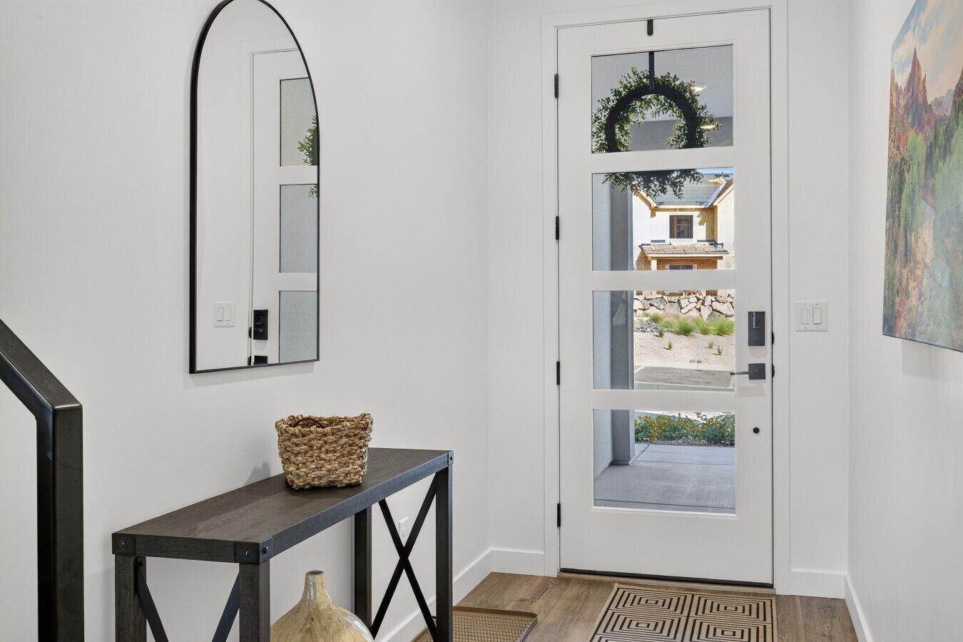 A modern entryway with a white door, a console table with a woven basket, a mirror, and a rug.