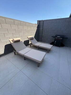 Eine Dachterrasse mit zwei Liegestühlen und einem Grill.