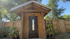 Una struttura in legno con una porta, un cartello sopra la porta e un piccolo oblò.