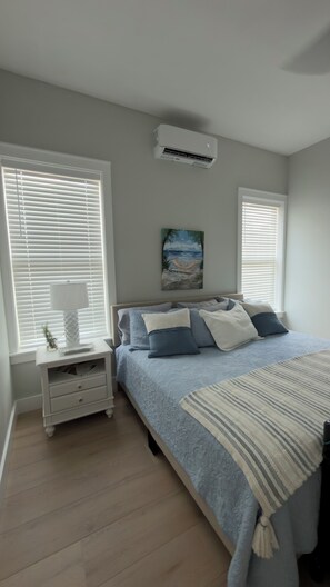 A bedroom with a bed, nightstand, lamp, air conditioner, and a painting on the wall. - NICEVILLE FLORIDA
Hammock Haven – Spacious, Serene & Just Minutes from the Beach (Niceville)