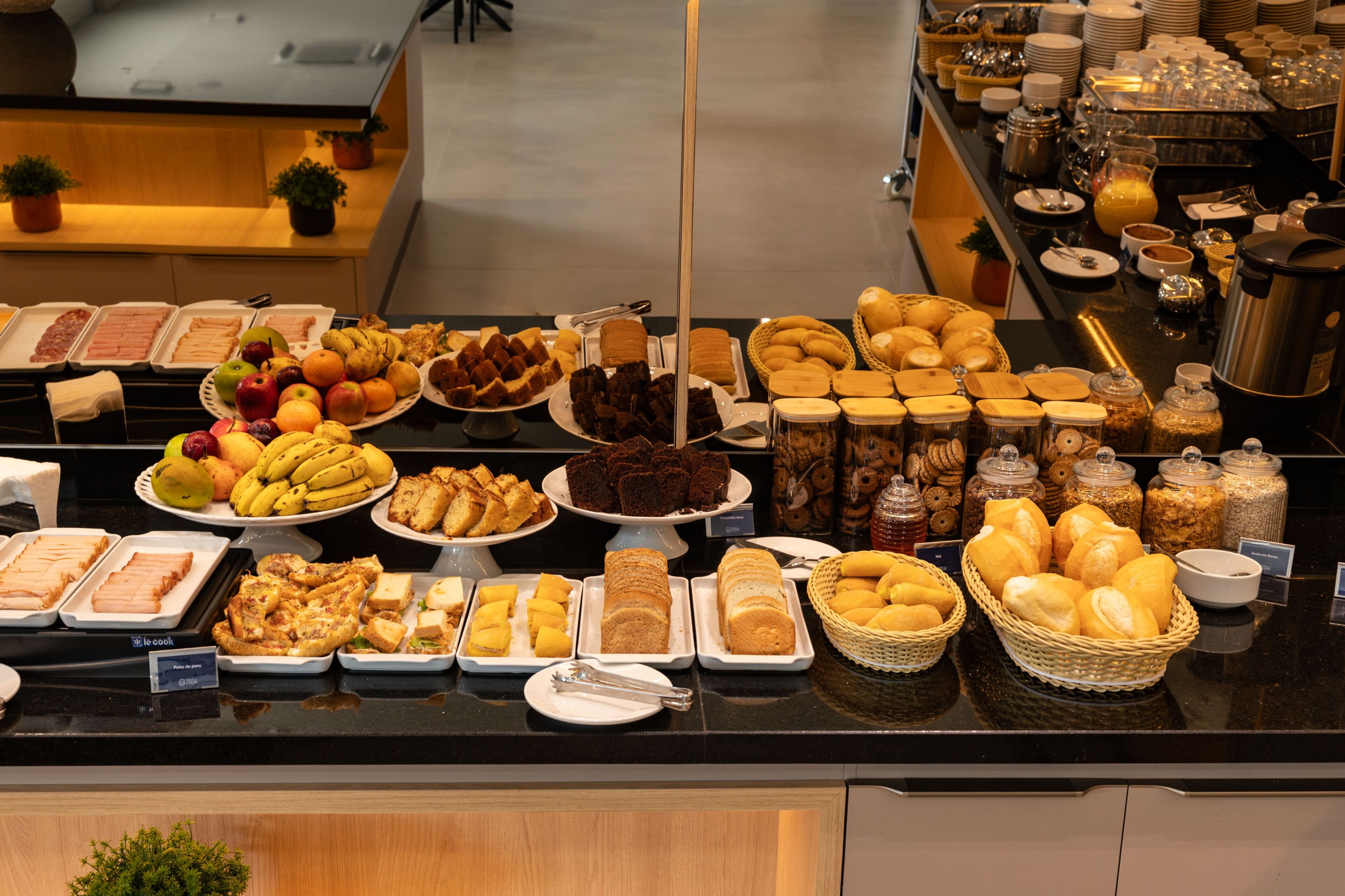 A buffet with various food items including fruits, breads, and pastries.
