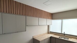 Une cuisine moderne dotée d’un évier encastré, d’un mur recouvert de panneaux en bois et d’un banc.