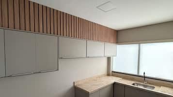 Cozinha moderna com pia embutida, painel de parede de madeira e um banco.