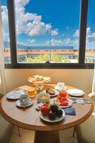 Una mesa de desayuno con diferentes alimentos y vista a un edificio a través de una ventana.